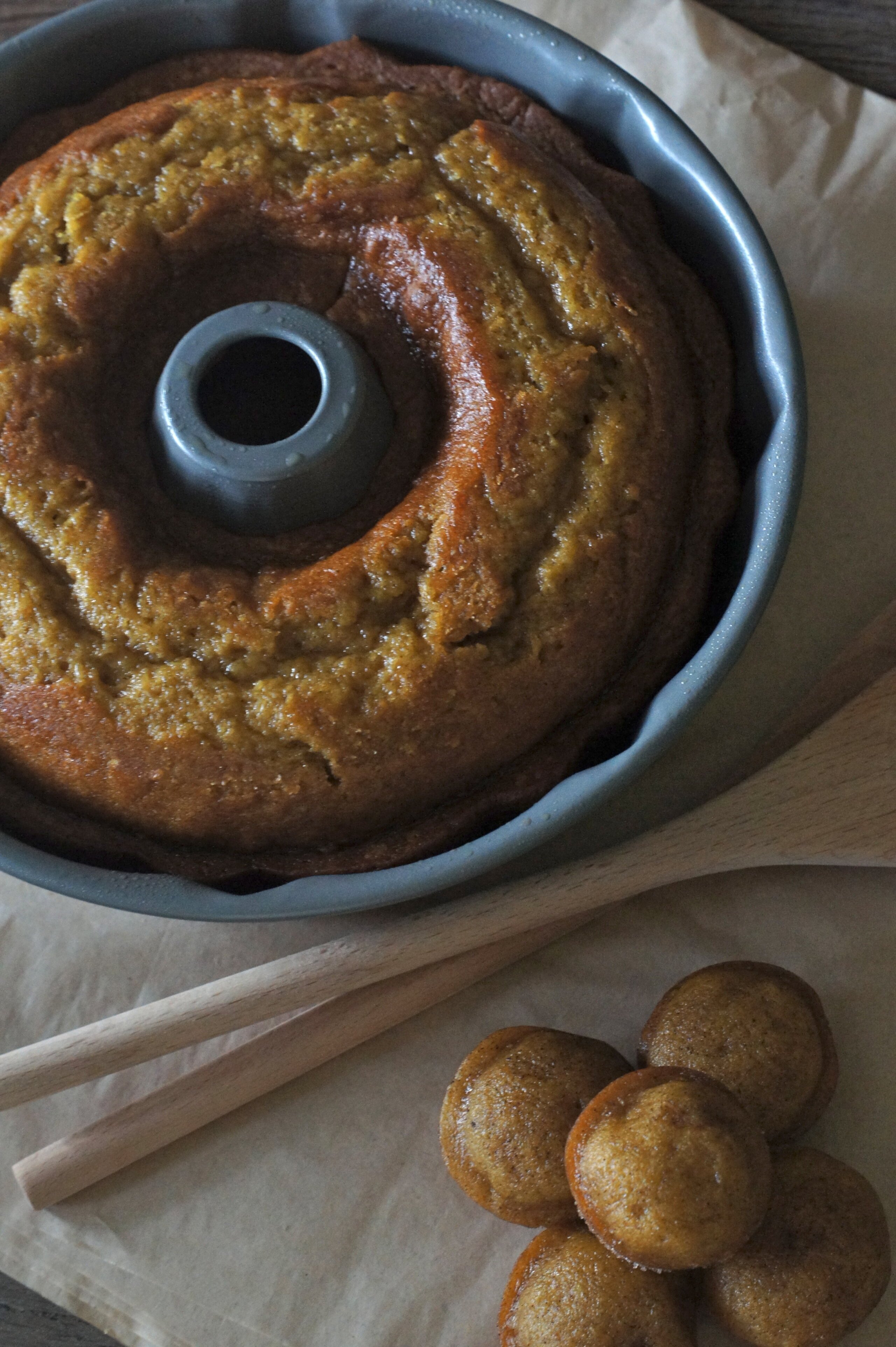 A freshly baked pumpkin ginger bundt cake in the bundt pan, with mini muffins beside it