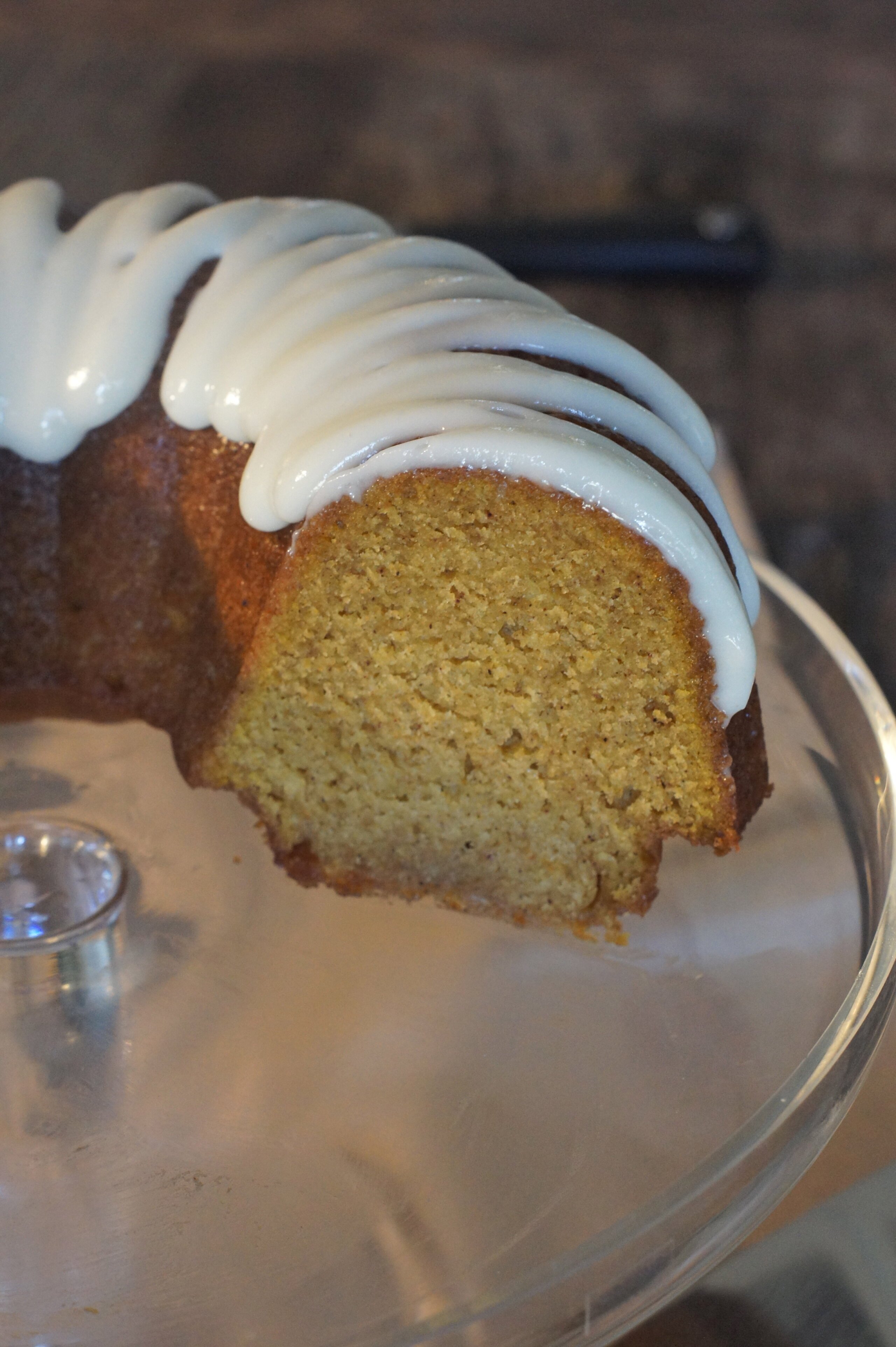 A cross section of a pumpkin ginger bundt cake, sitting on a glass cake stand