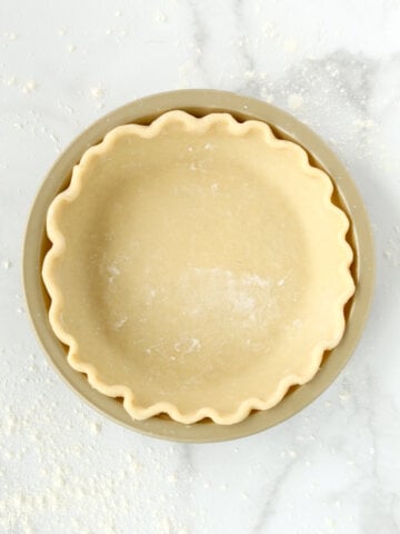 A gold pie dish with pie dough inside.