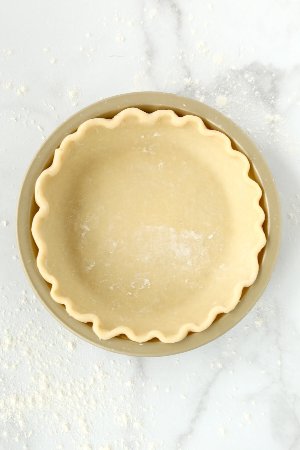 A gold pie dish with pie dough inside.  
