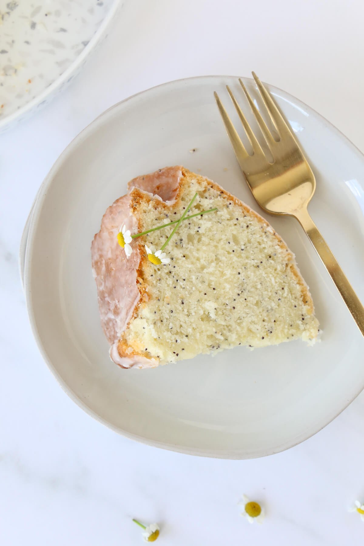 A Slice of lemon cake on a plate with a gold fork.  