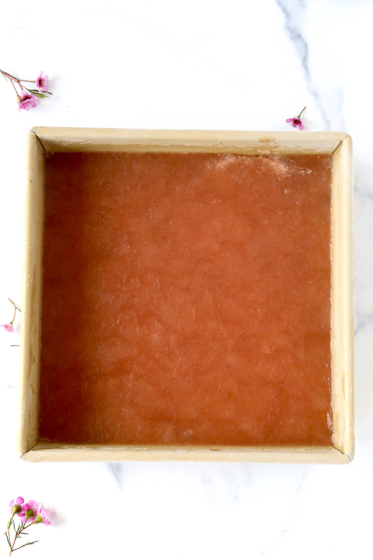 A square pan filled with a pink frozen liquid.