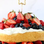 A layer of sponge cake with fresh whipped cream and berries and a star candle.