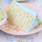 a slice of vanilla cake on a pink plate with rainbow sprinkles