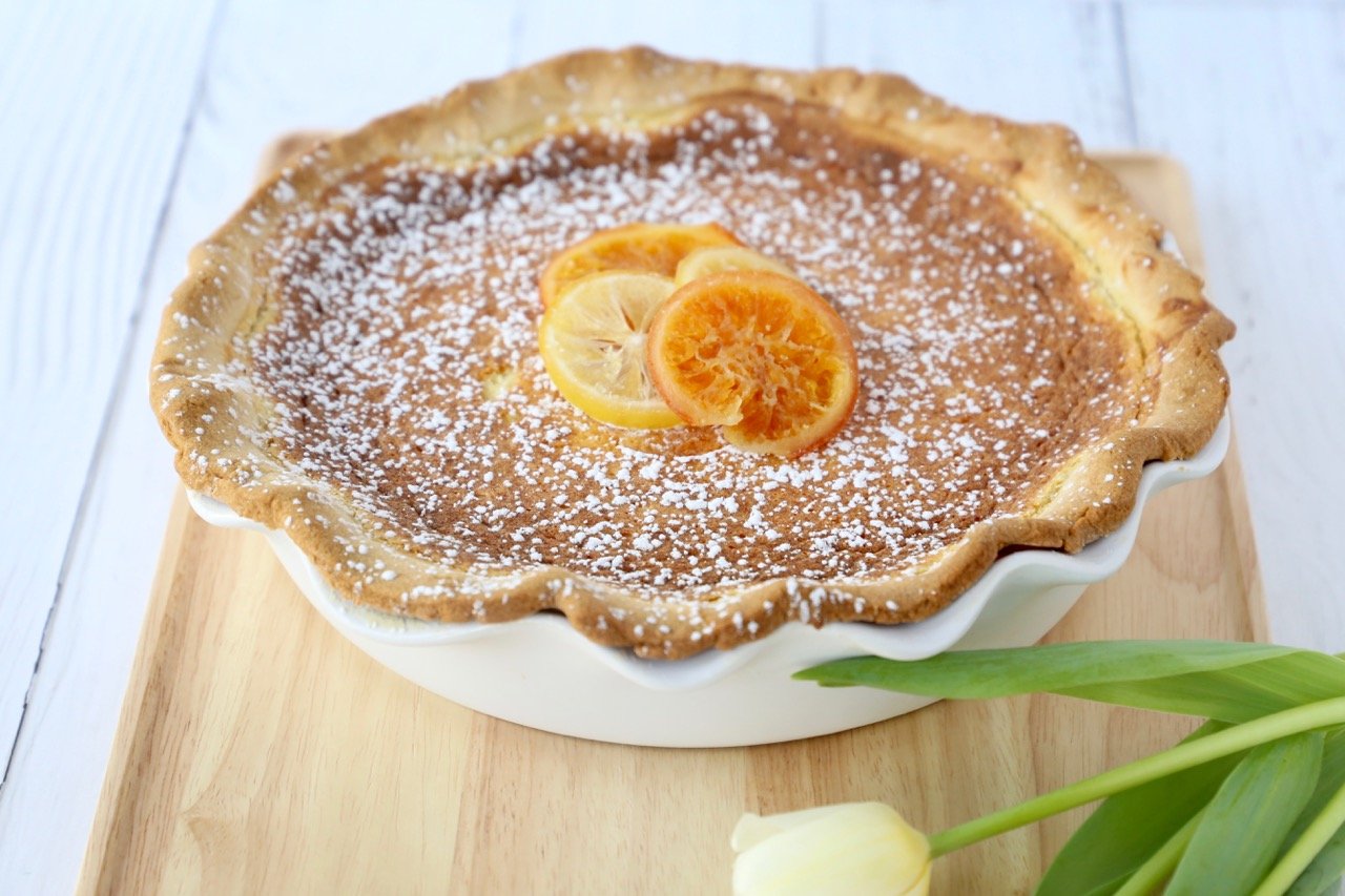 A finished Easter Grain Pie on a wooden tray next to a tulip