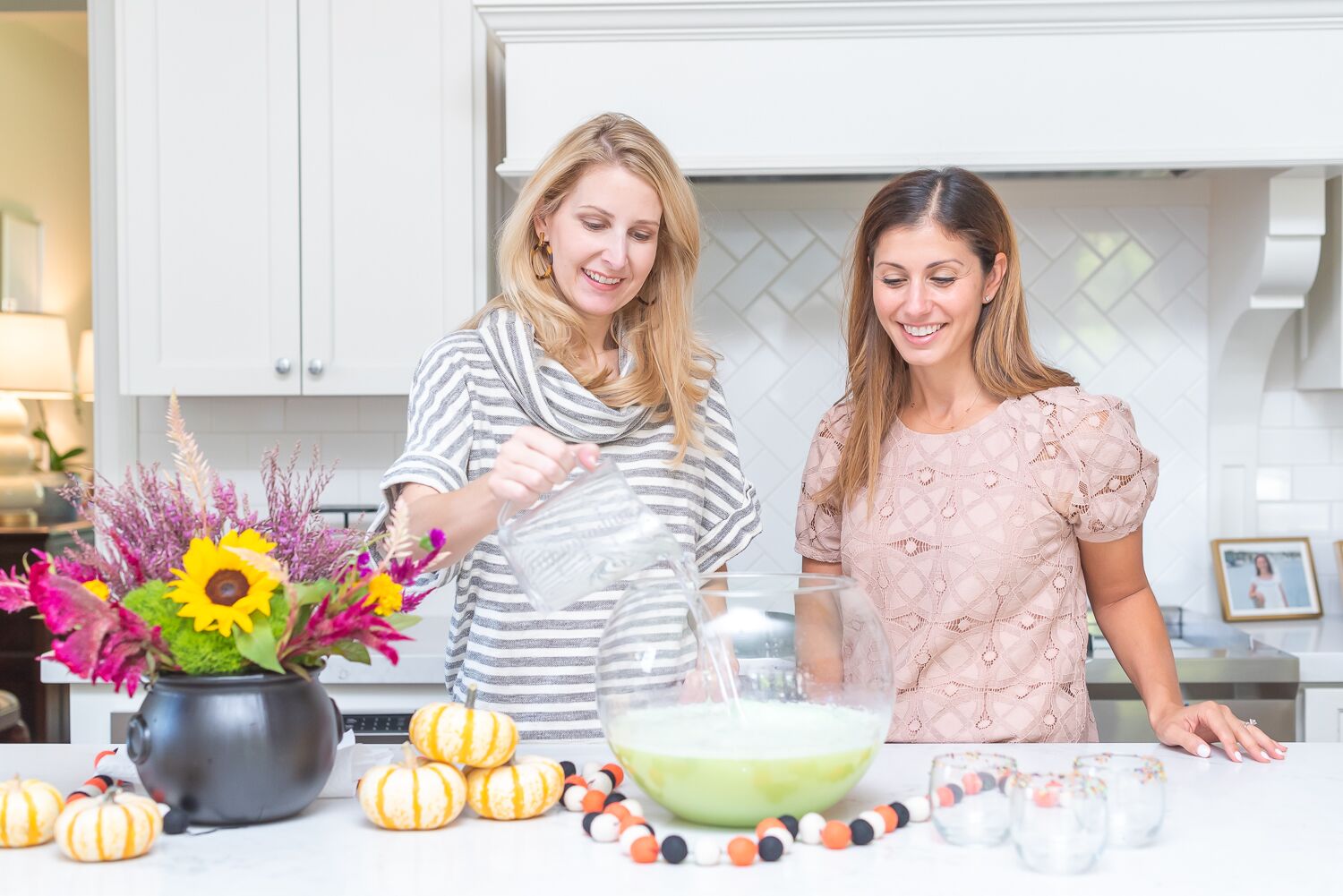 2 women pouring Sprite into a large punch bowl