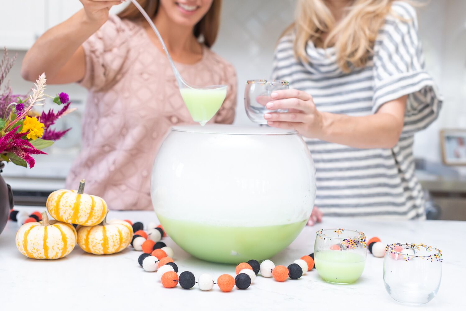 2 women using a ladle to pour punch into a glass