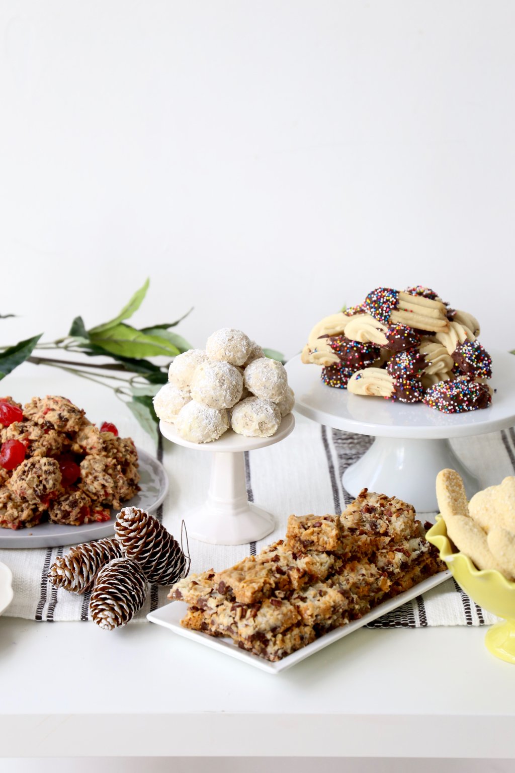 A table full of cookies on plates and cake stands. 