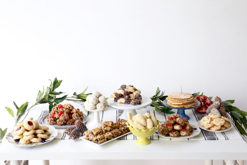 A table filled with assorted cookies on plates and cakes stands.  