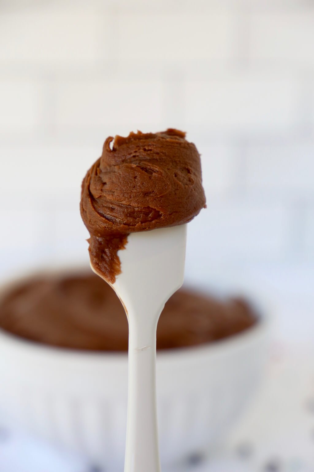 A white spoon covered in chocolate buttercream frosting