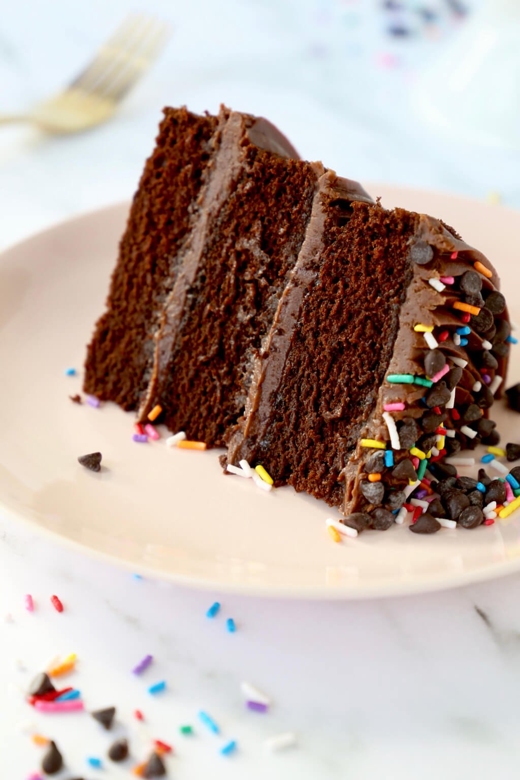 A slice of chocolate layer cake frosted with chocolate buttercream frosting