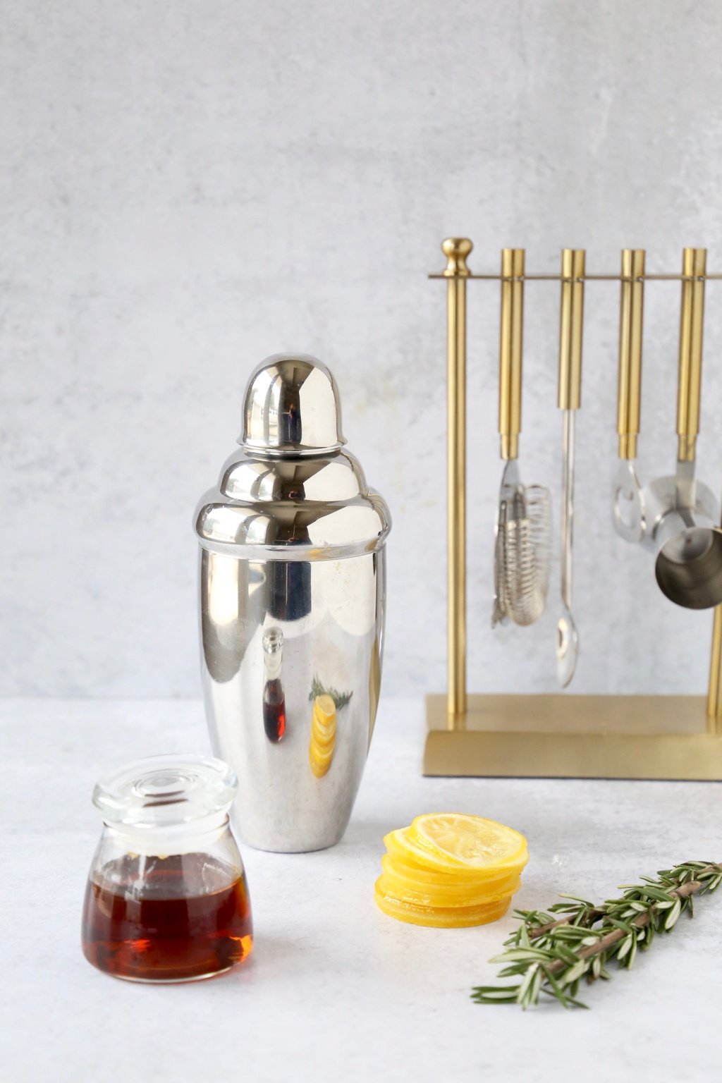 barware with sliced candied lemons, rosemary sprigs and maple syrup