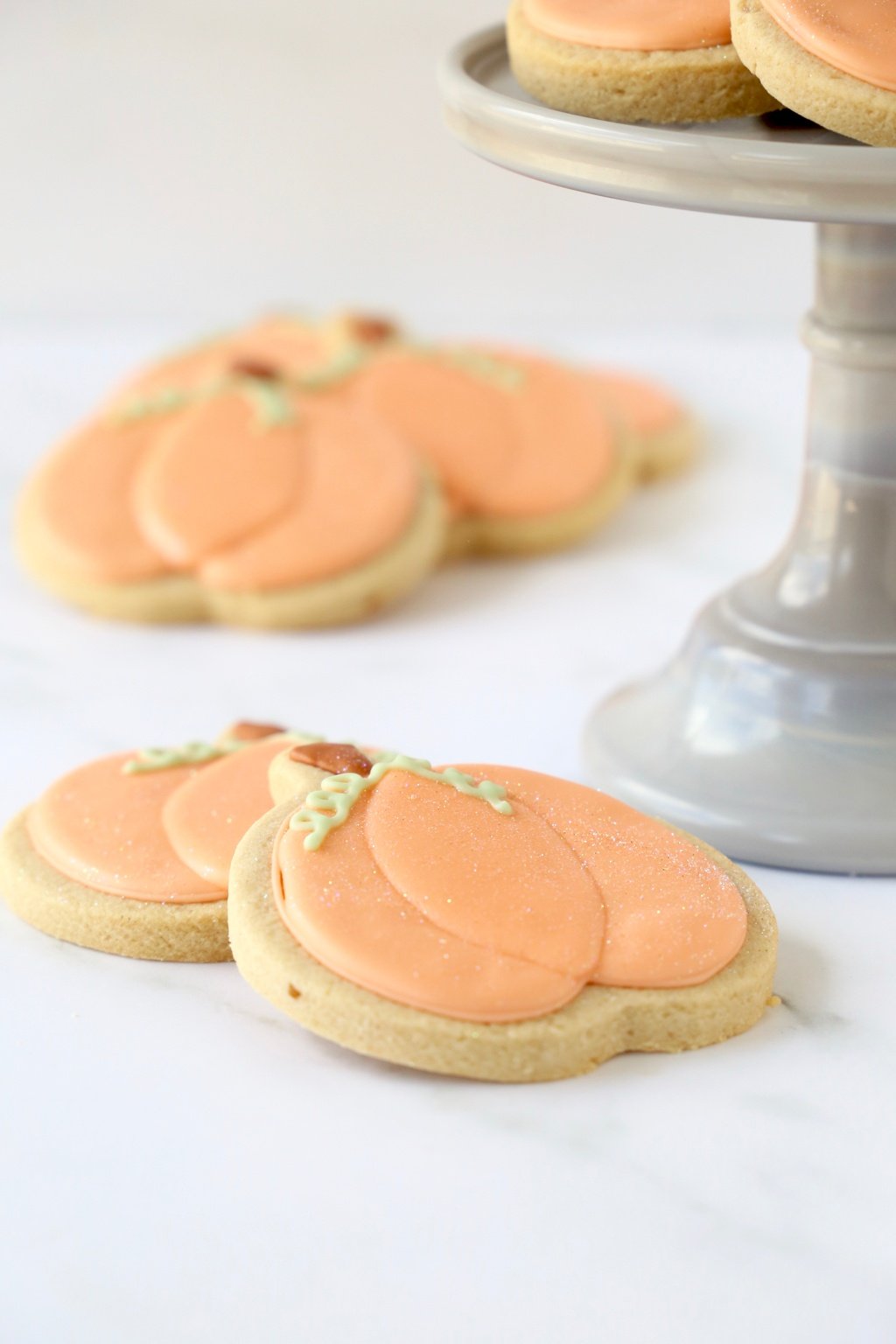 A close up of 2 spiced shortbread cookies decorated like pumpkins