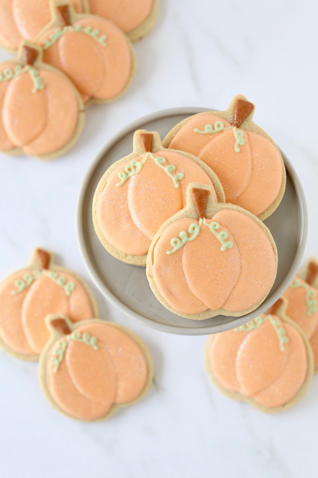 A close up of 3 spiced shortbread cookies, decorated to look like pumpkins