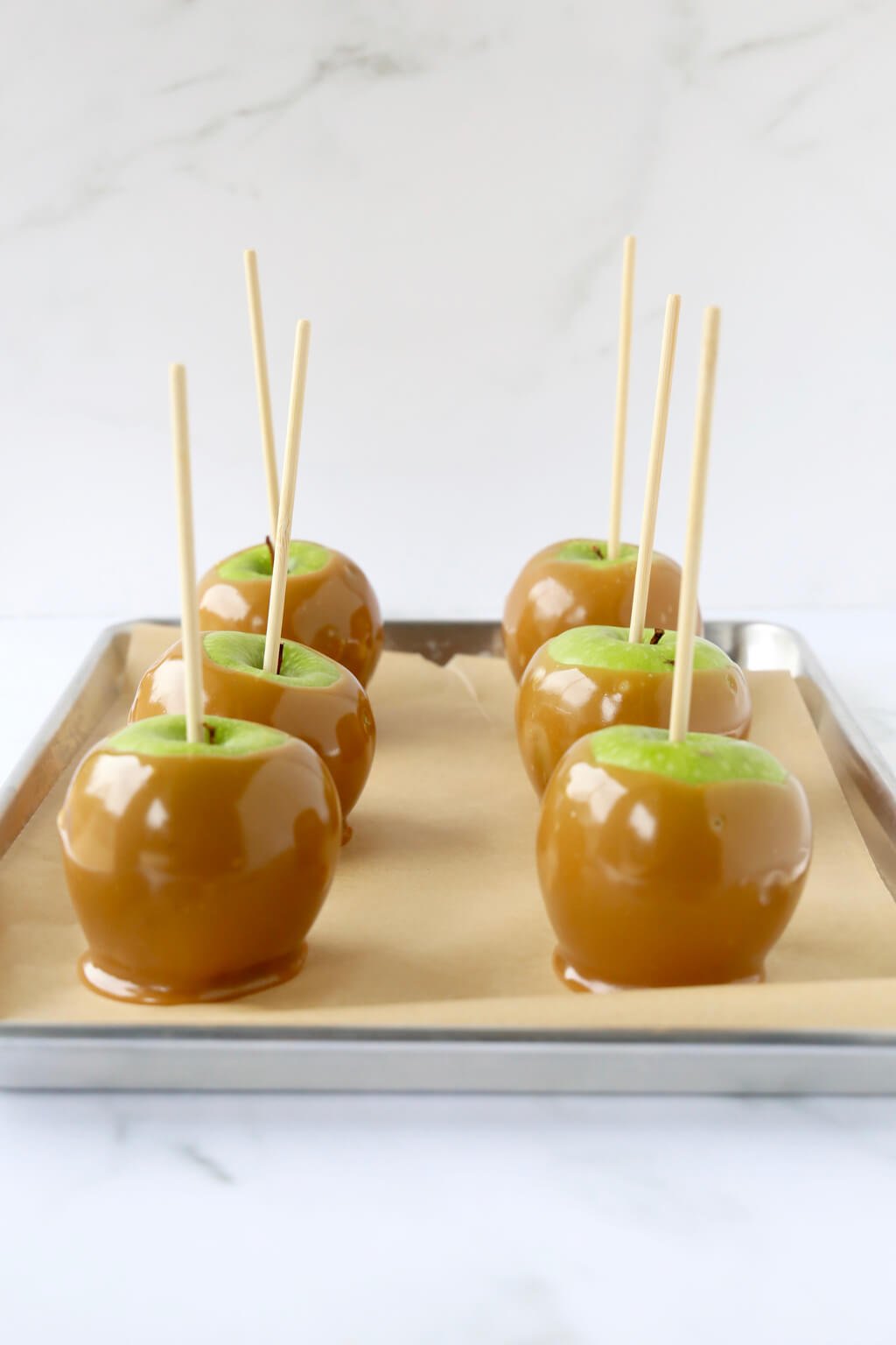 6 caramel apples sitting on a tray