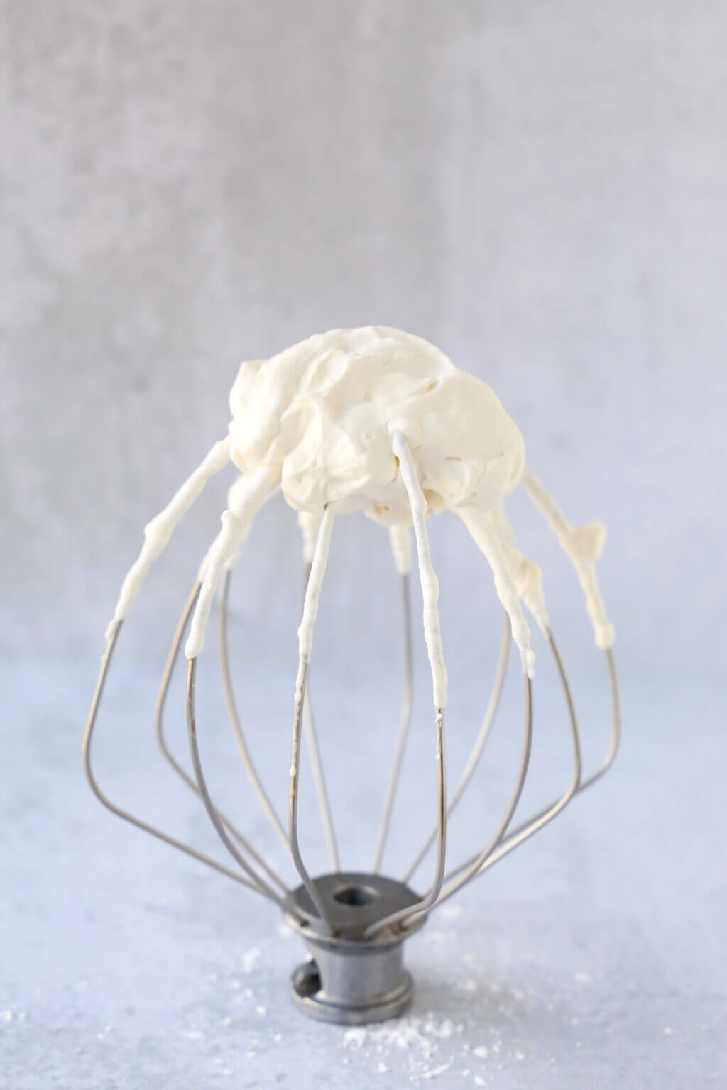 A whisk with cream on the top of it. 