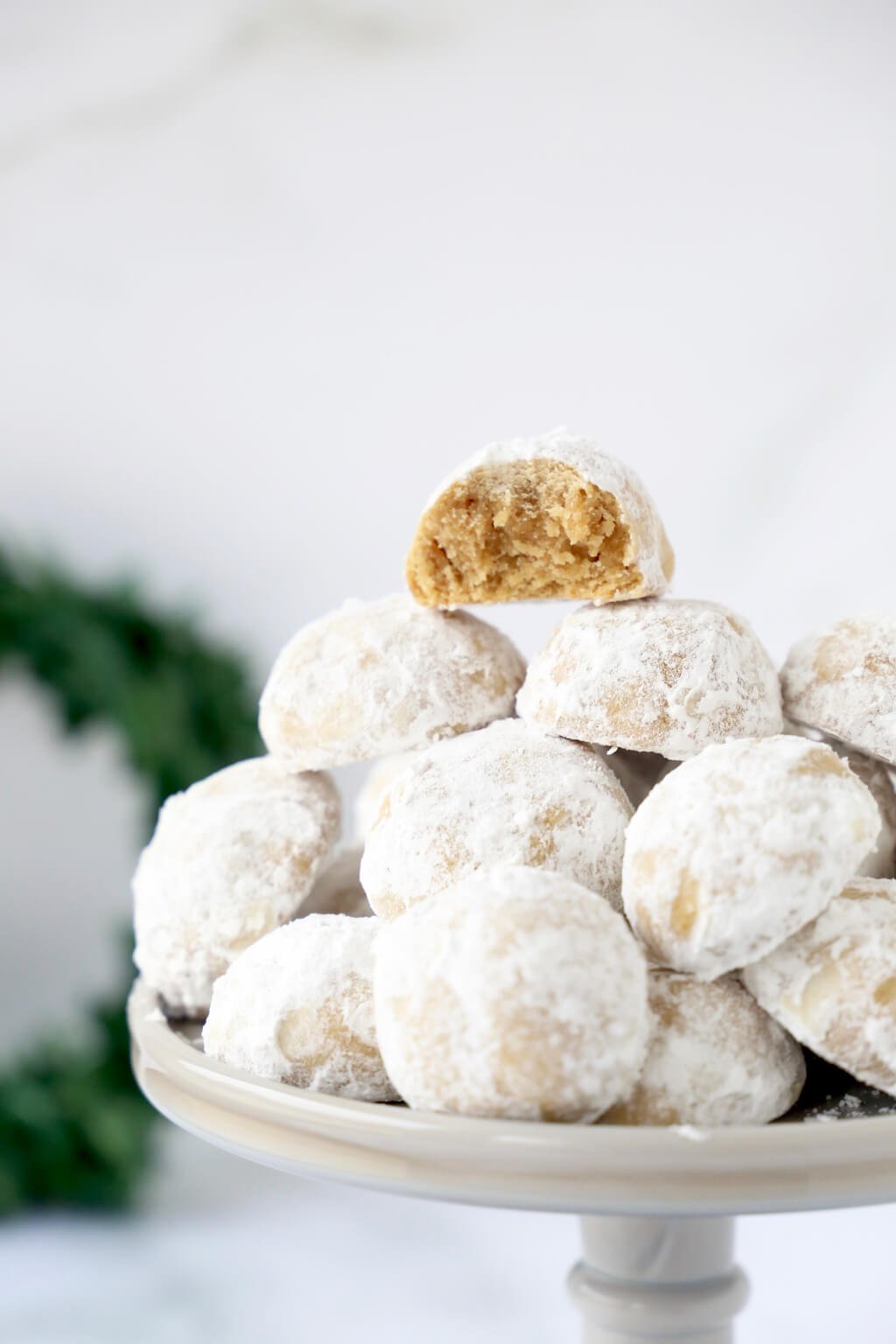 a close up shot of gingerbread snowball cookies, one with a bite taken out 
