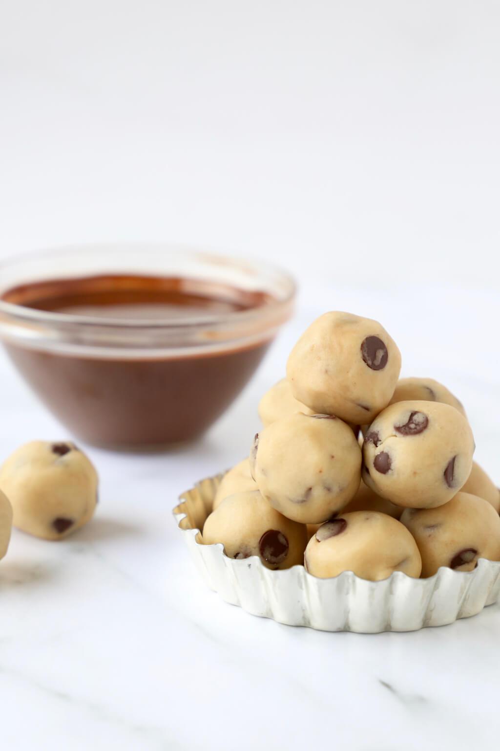 a pile of chocolate chip cookie dough balls ready to be dipped in chocolate glaze