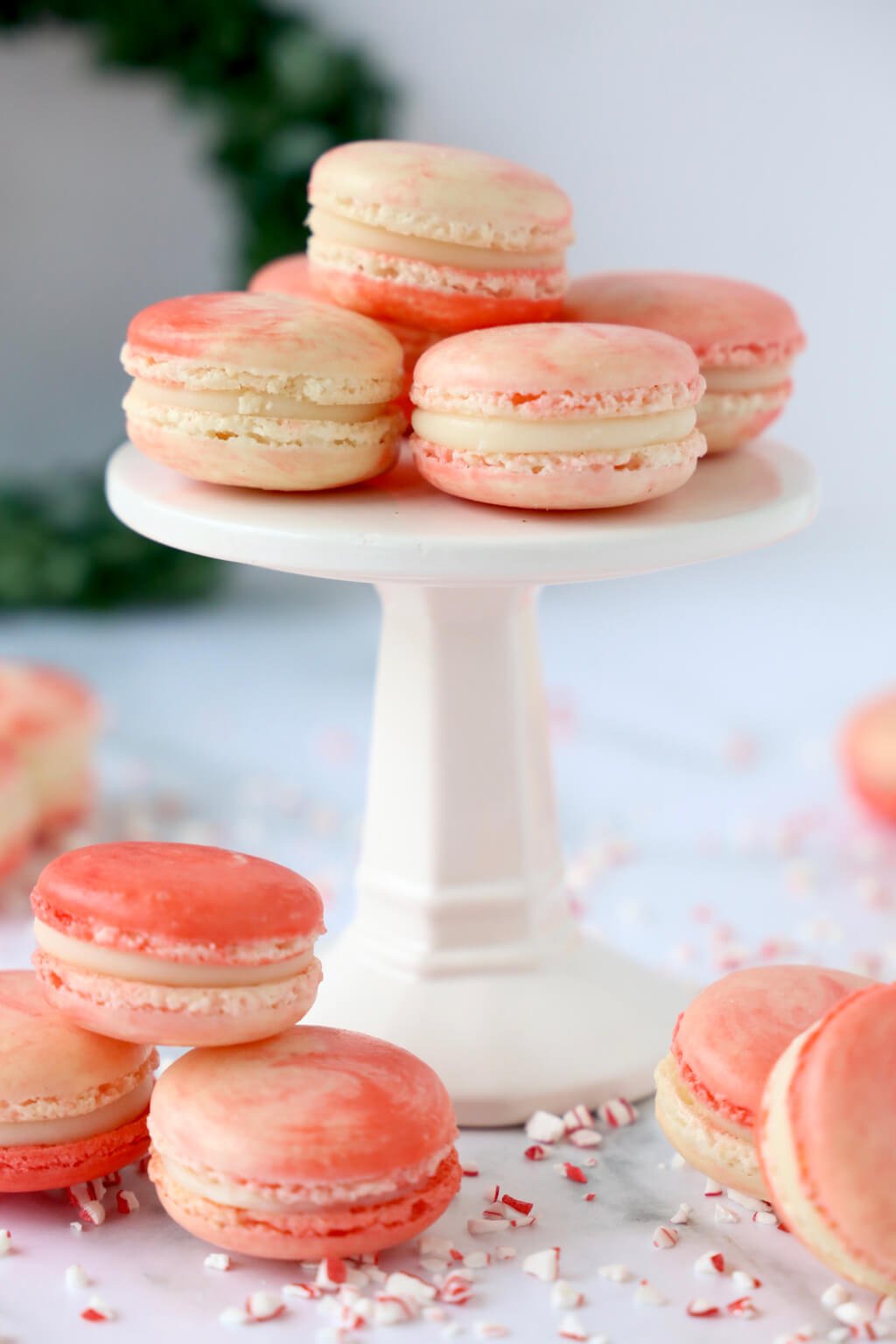 Peppermint white chocolate french macarons sitting on a white cake stand, with a few around the base