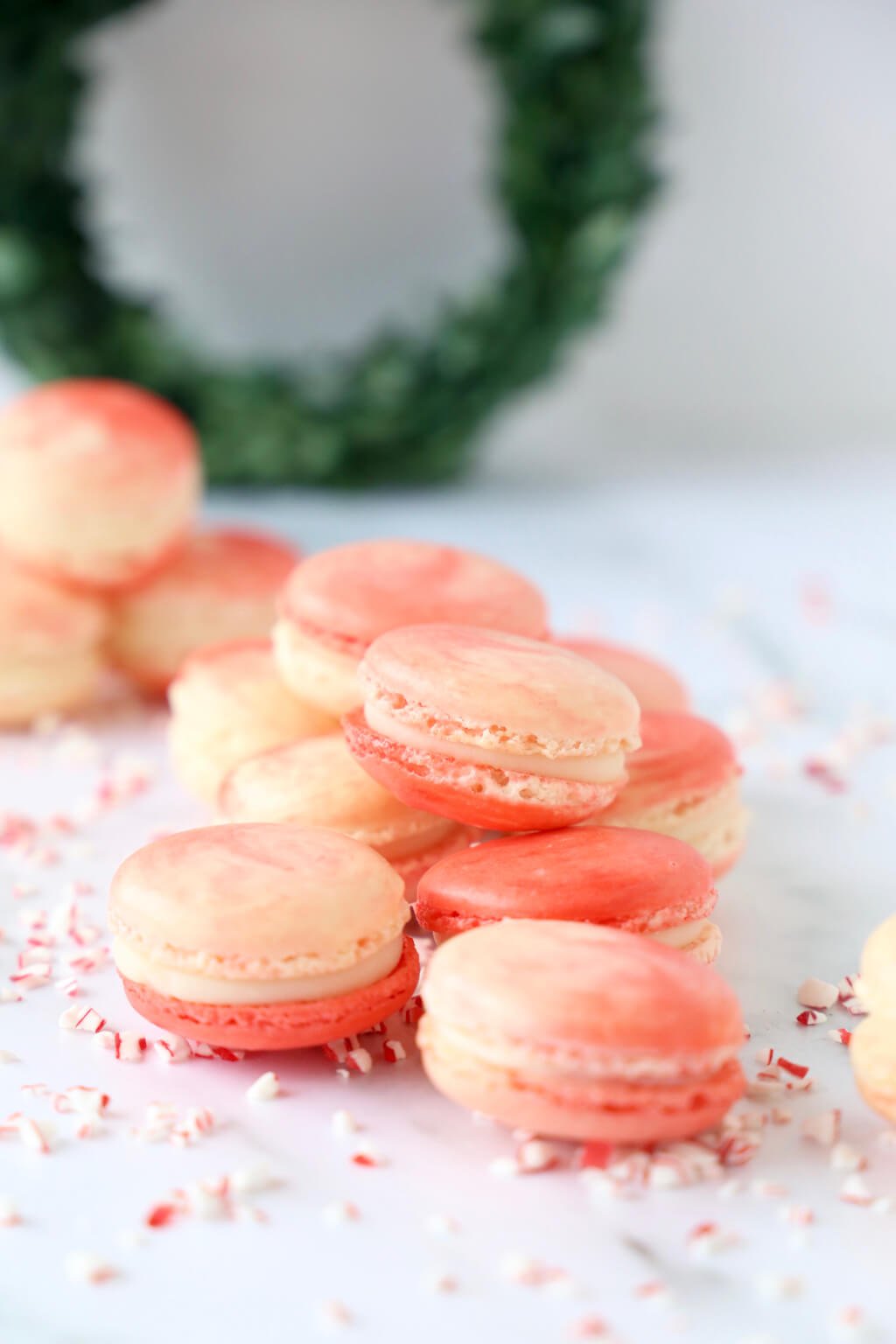 Close up of several peppermint white chocolate french macarons, surrounded by pieces of peppermint