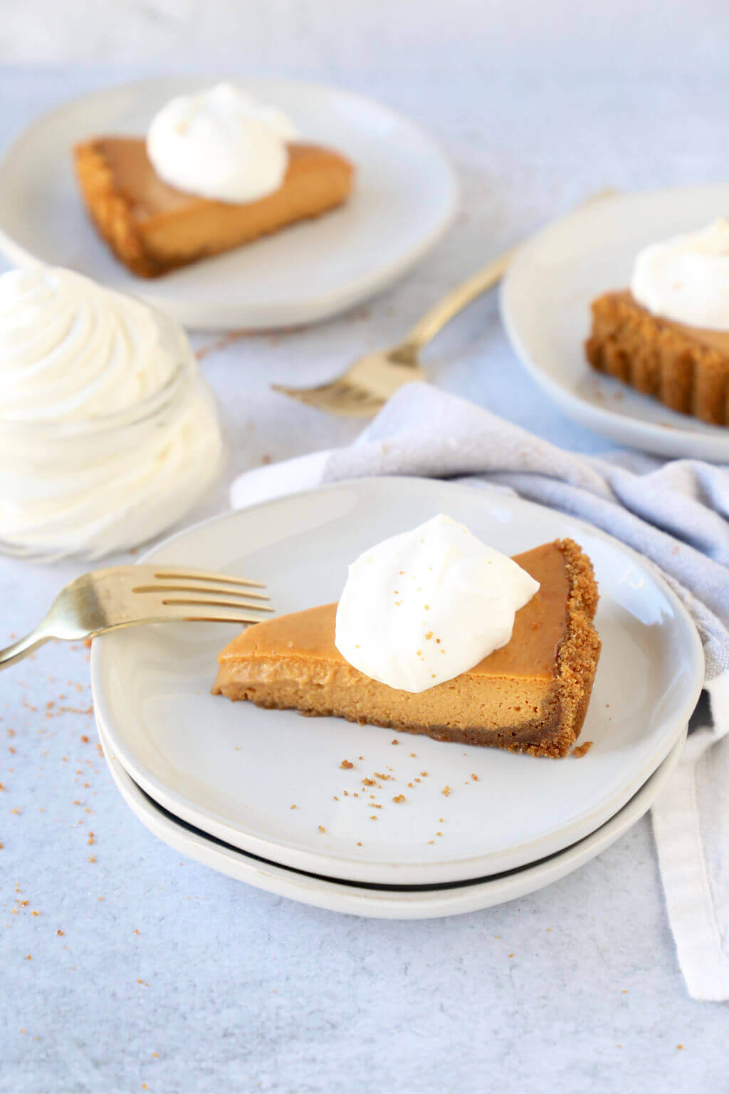 A slice of pumpkin gingersnap tart topped with whipped cream, with a few more slices sitting in the background