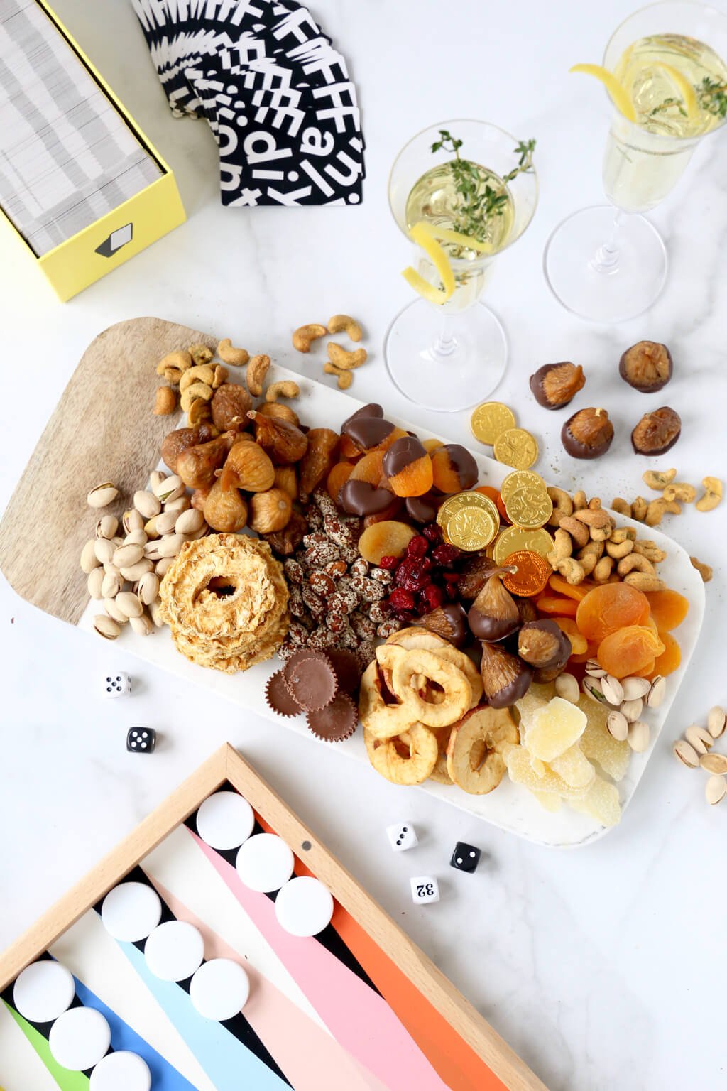 card game, backgammon game and a snack board with two glasses of champagne