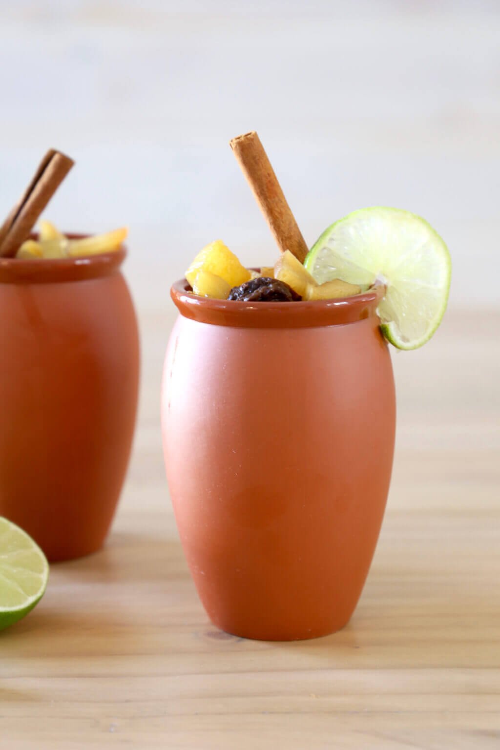 two clay mugs filled with christmas punch and a cinnamon stick