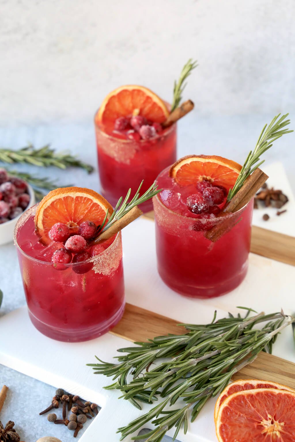 three glasses of a christmas cocktail with rosemary, cinnamon and dried grapefruit 