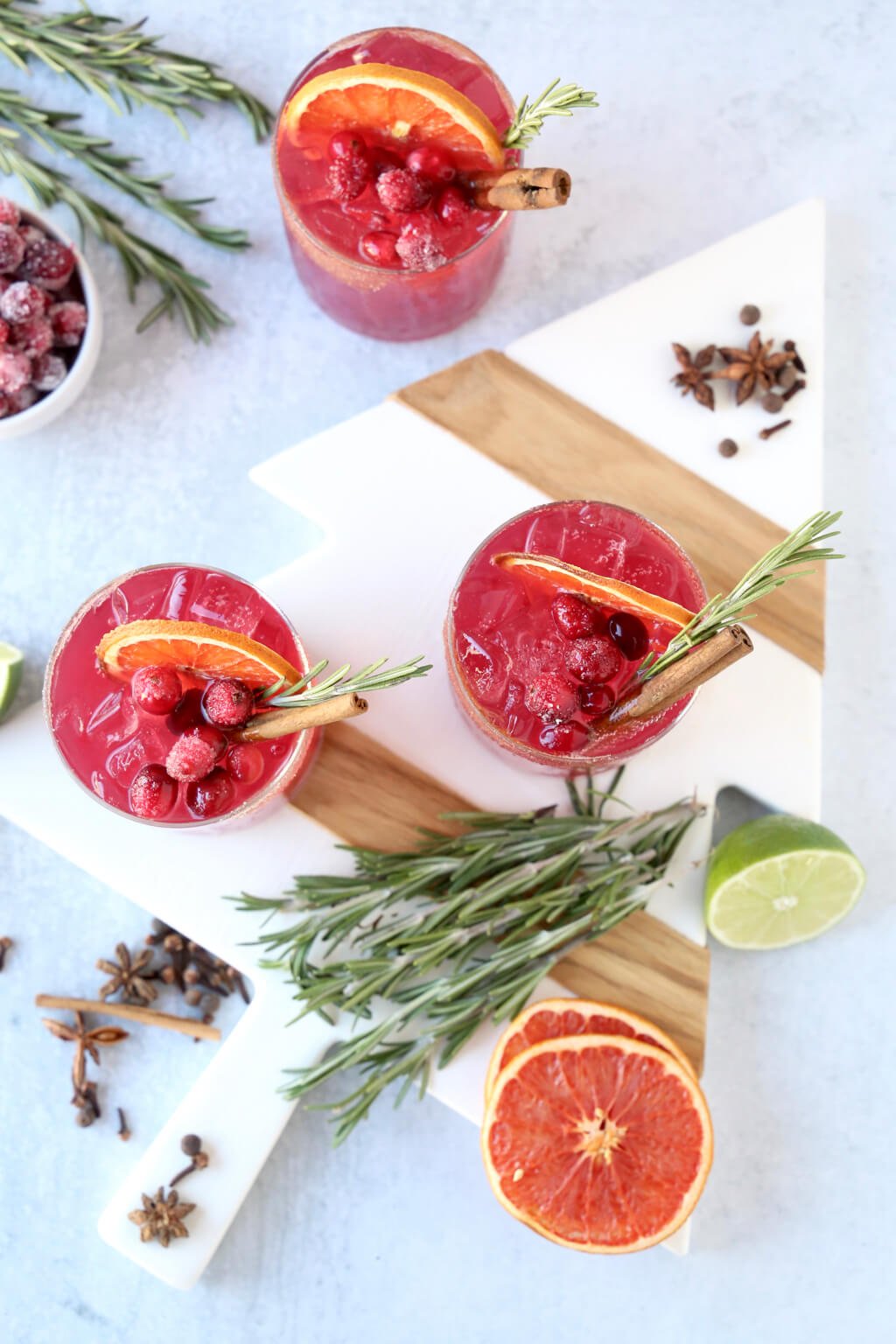 three glasses of a christmas cocktail with rosemary, cinnamon and dried grapefruit 
