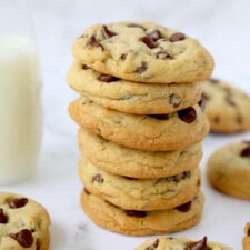 a stack of six chocolate chip cookies in front of a glass of milk