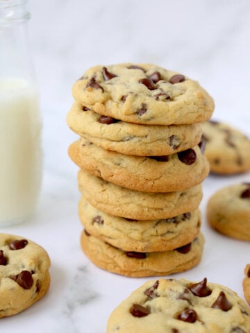 a stack of six chocolate chip cookies in front of a glass of milk