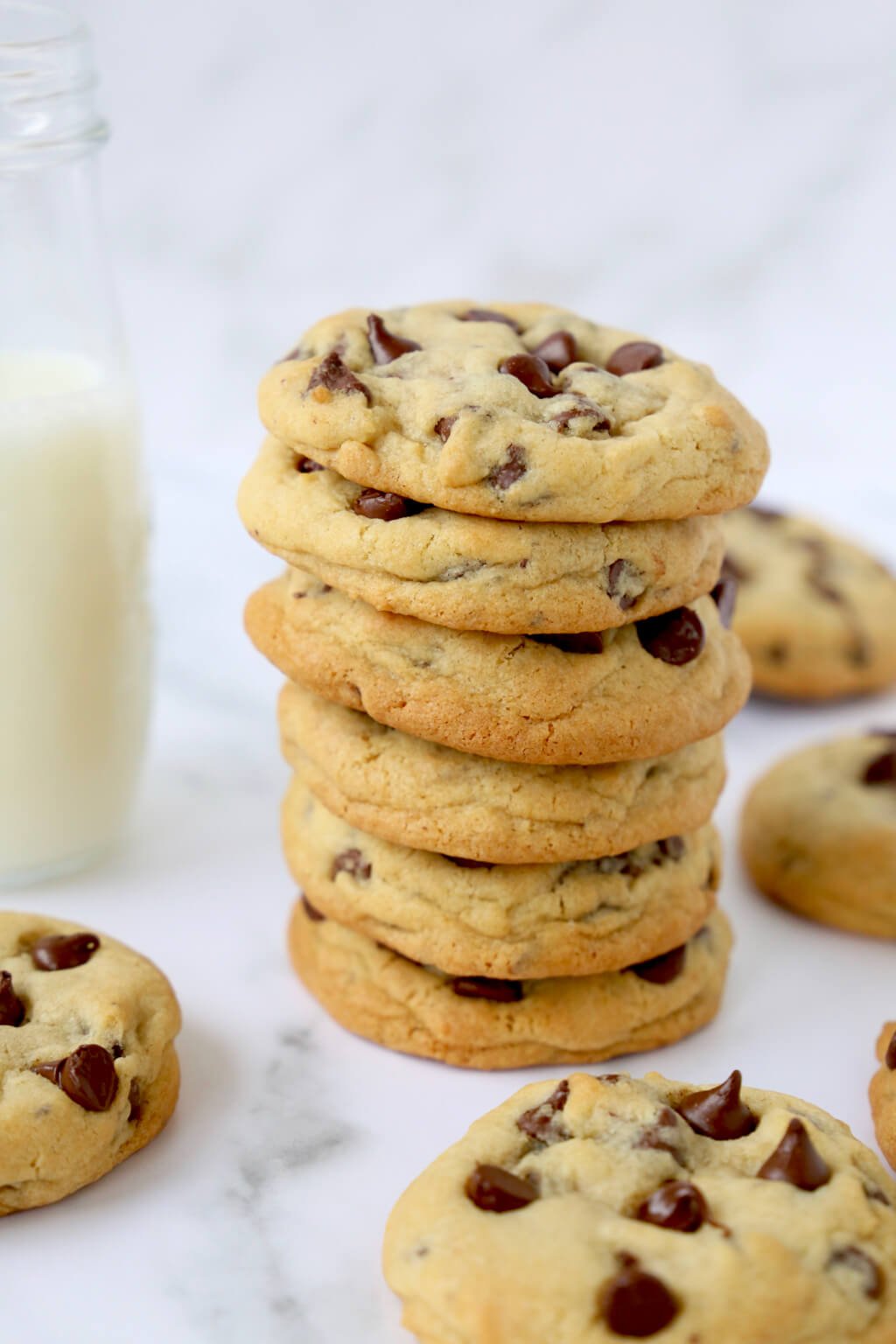 a stack of six chocolate chip cookies in front of a glass of milk