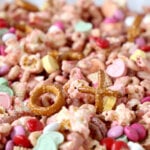 a sheet pan of snack mix made of chex, cheerios, popcorn, pretzels, m&m's and conversation hearts
