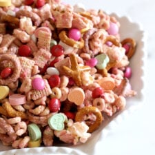 a bowl of snack mix with pretzels, chex mix, popcorn, cheerios and m&m's