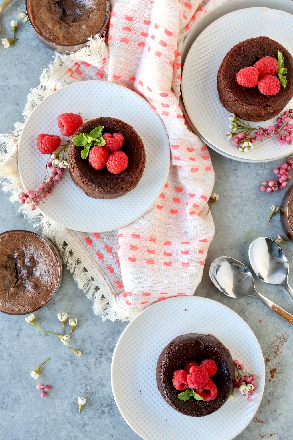 a table filled with chocolate cakes on dessert plates, garnished with raspberries