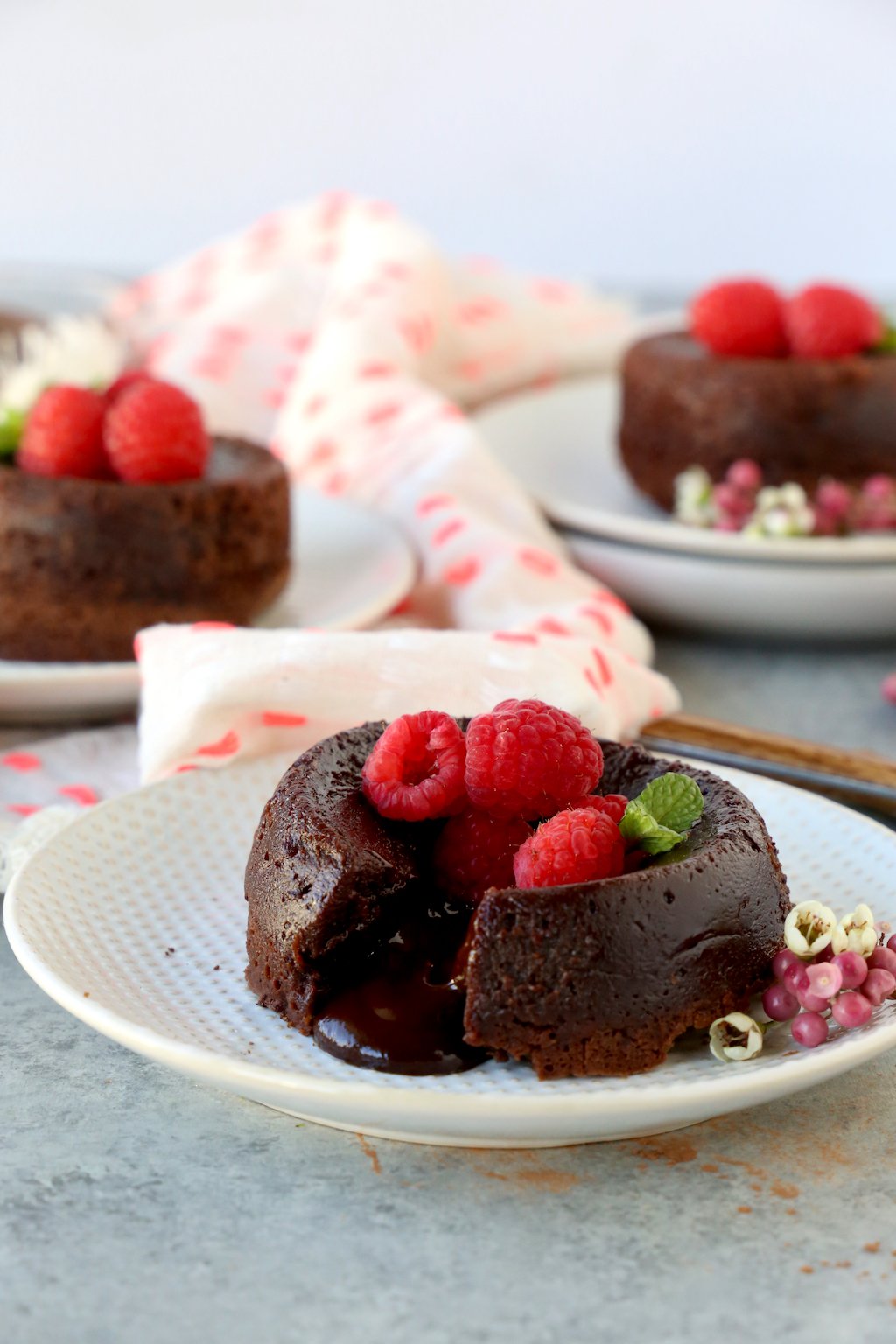 three chocolate cakes with raspberry on top and a pink and white napkin 