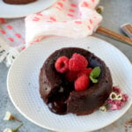 an individual chocolate cake on a dessert plate garnished with raspberries