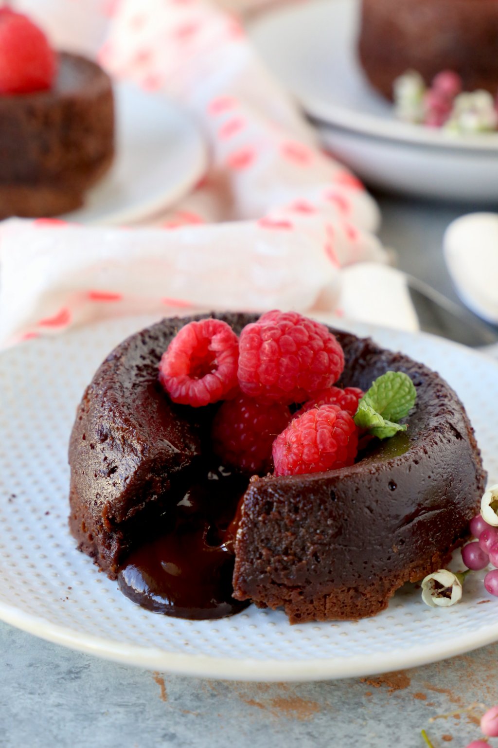 Close up of a molten chocolate cake garnished with raspberries and mint