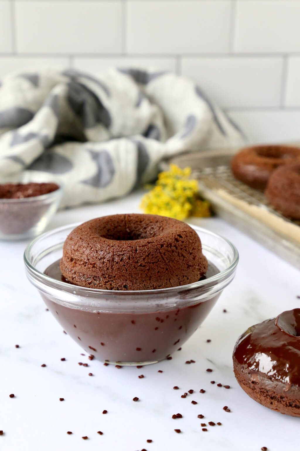 a bake donut dipped in a bowl of chocolate ganache