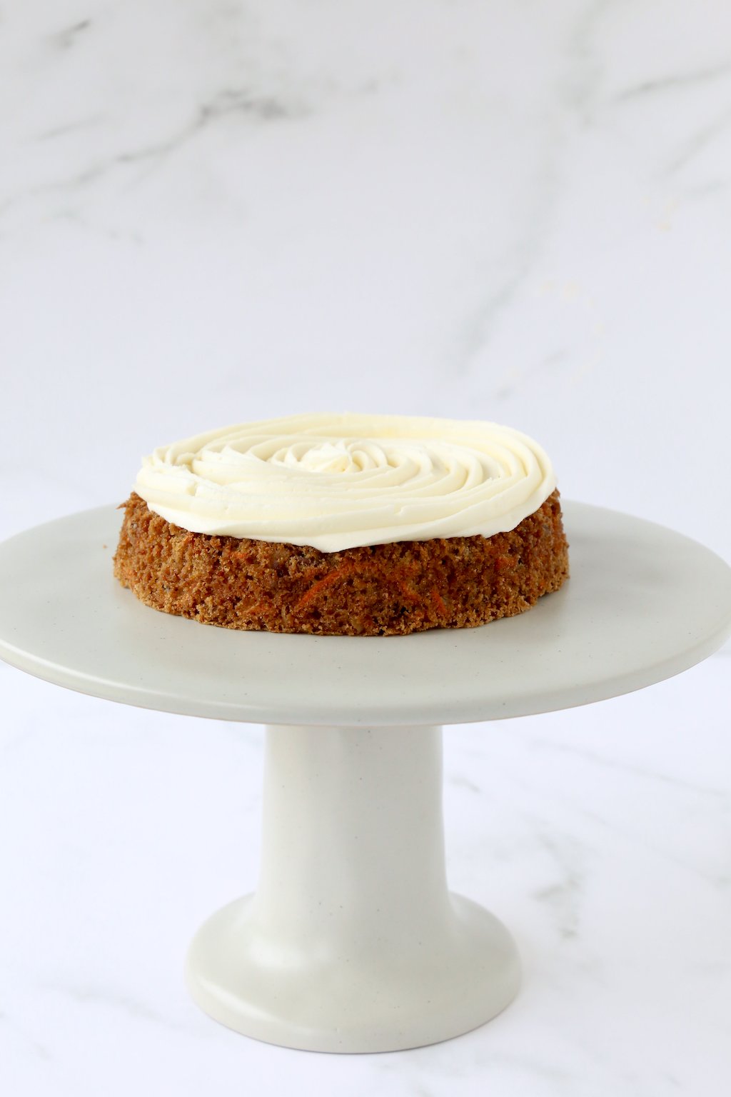 one layer of carrot cake with cream cheese frosting on a cake stand