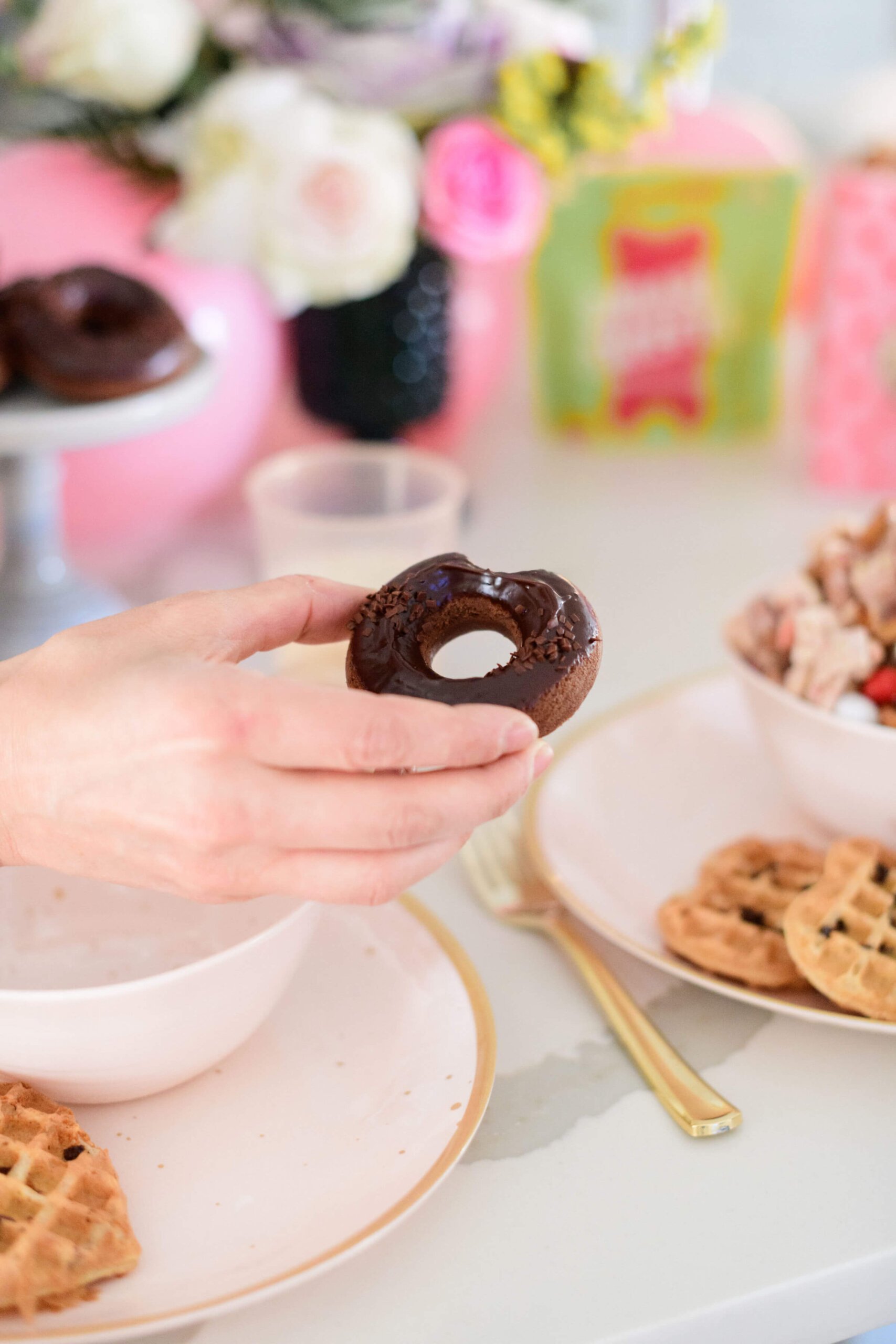 a hand holding a chocolate baked donut 