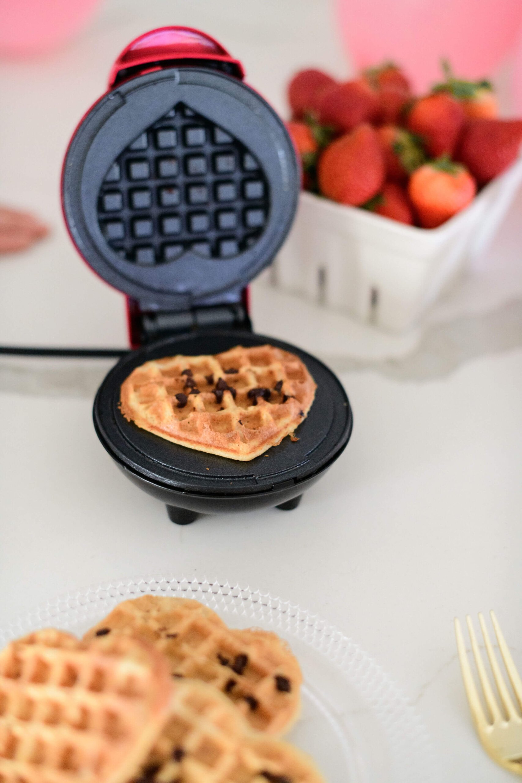 a waffle maker opened with a chocolate chip waffle inside 