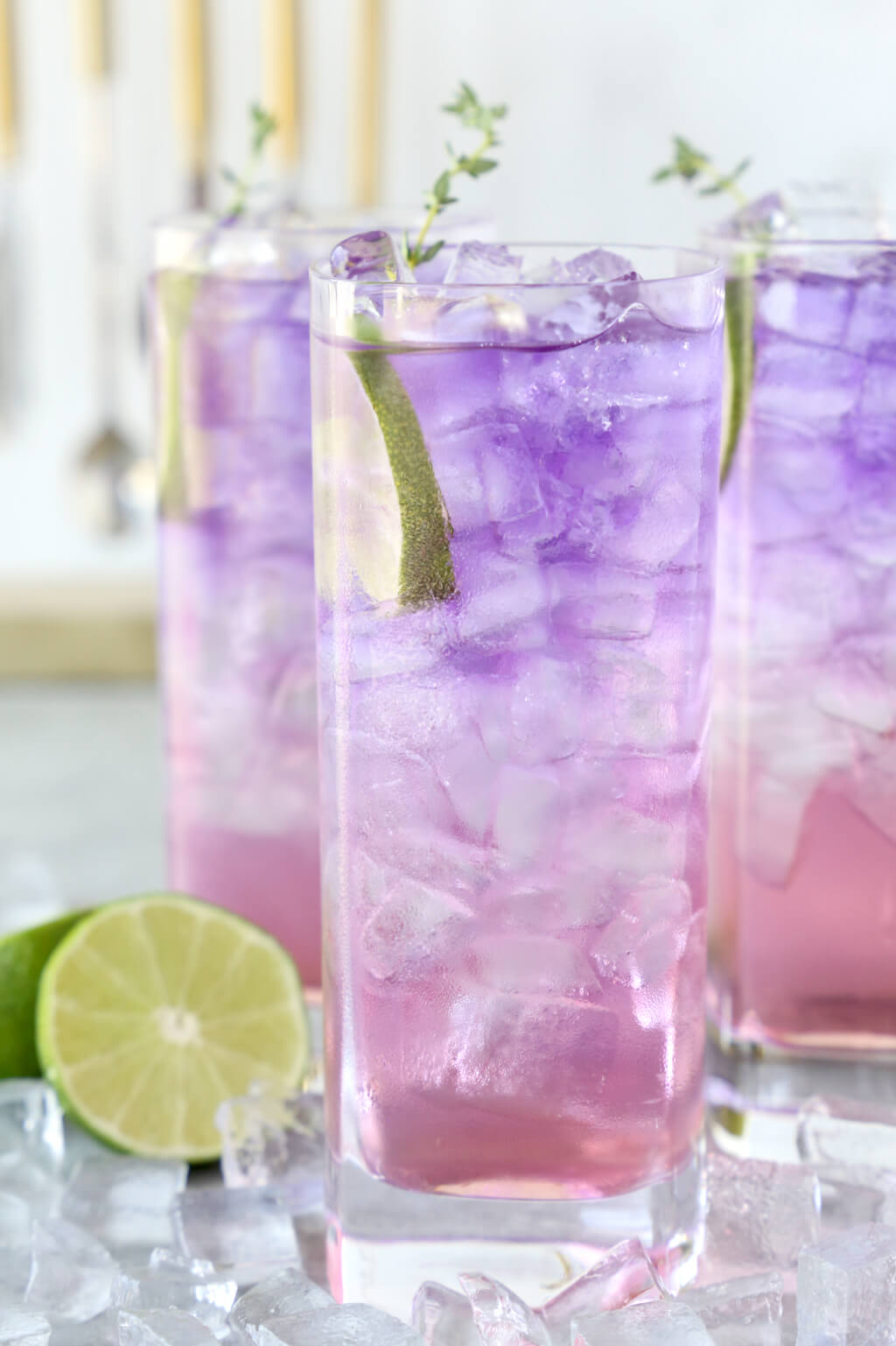 three glasses filled with ice and a purple and pink drink
