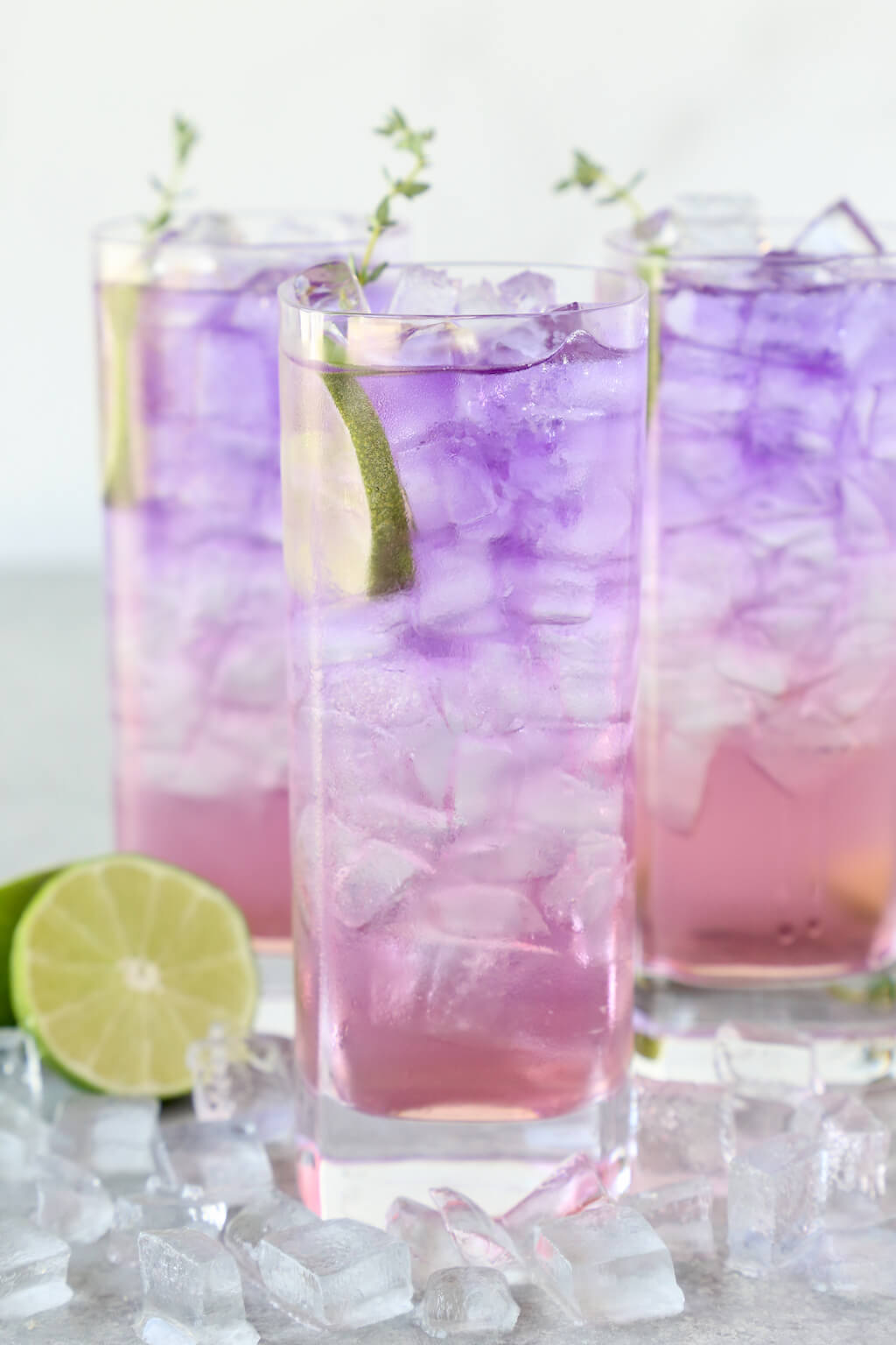 three glasses filled with ice and a purple and pink drink
