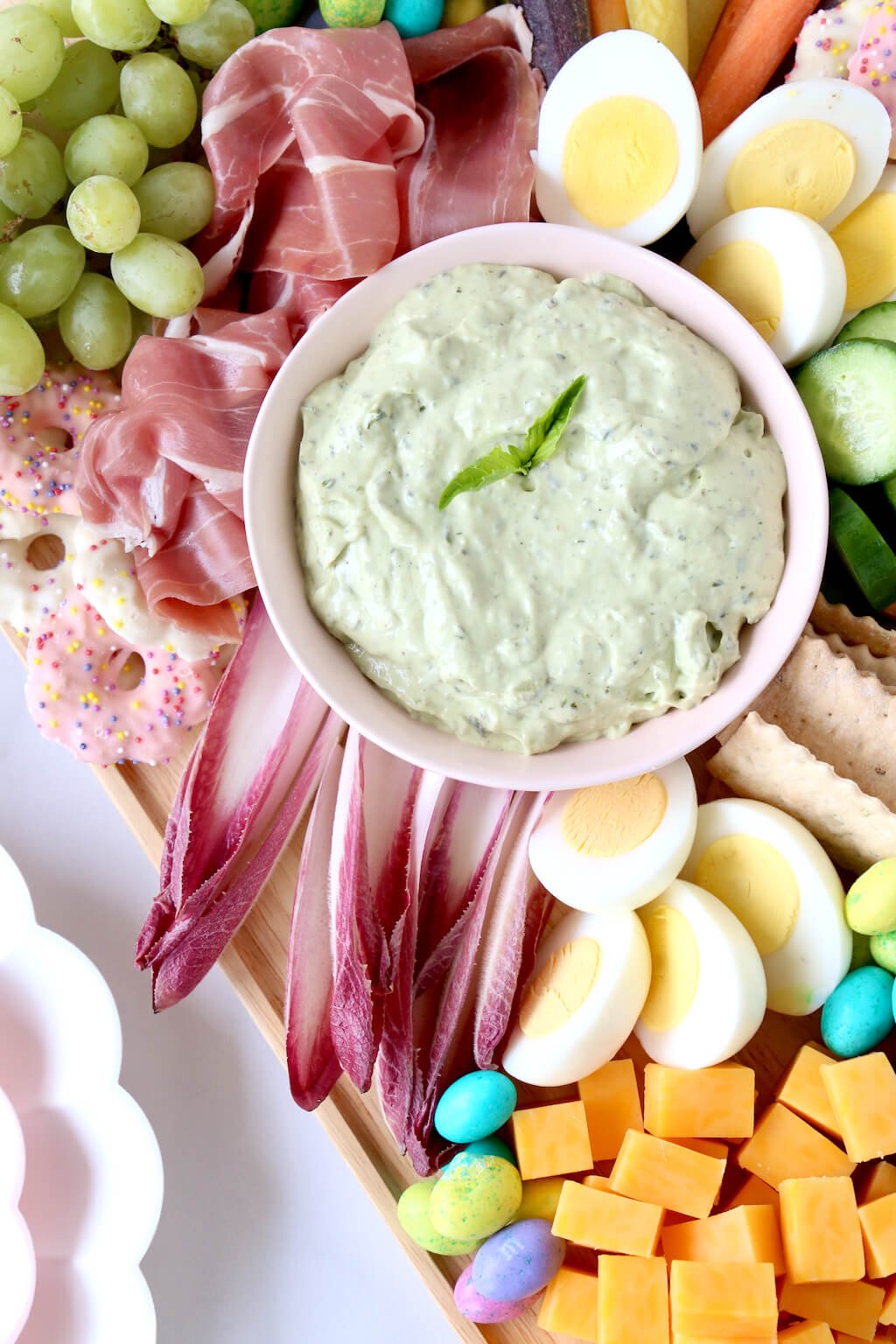 a platter of meats, cheeses, veggies and chocolate with a green dip 