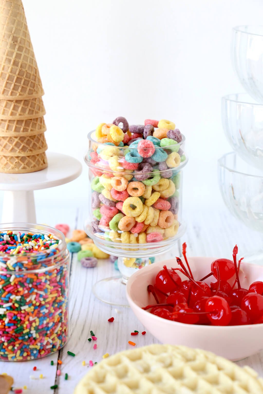 cereal, sprinkles, cherries, waffles cones and waffles on a table