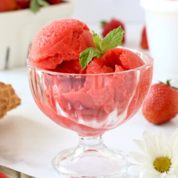 A glass bowl of three scoops of sorbet and fresh mint.