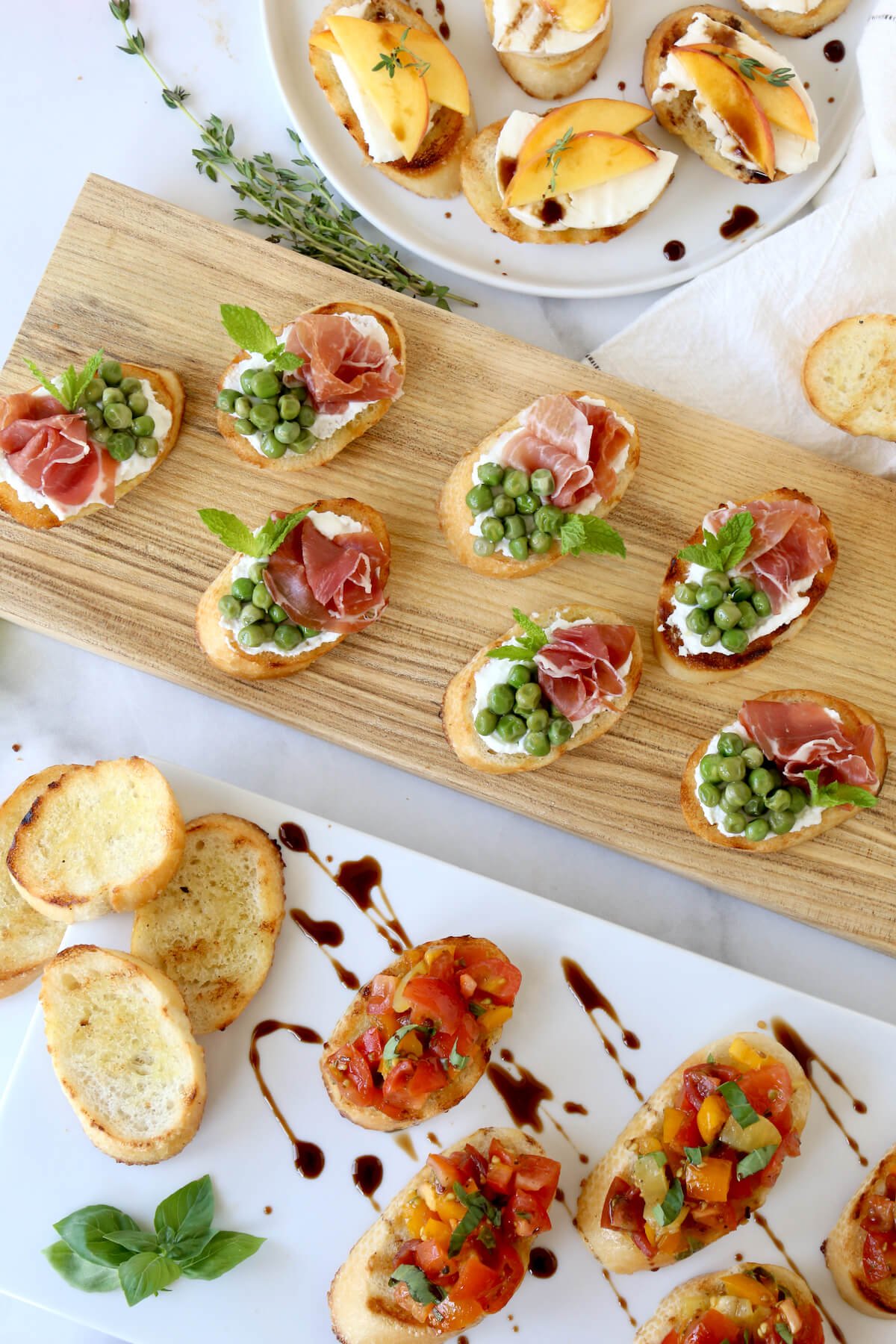 Three platter of assorted bruschetta, toasted bread with tomatoes, peas, prosciutto and peaches.  