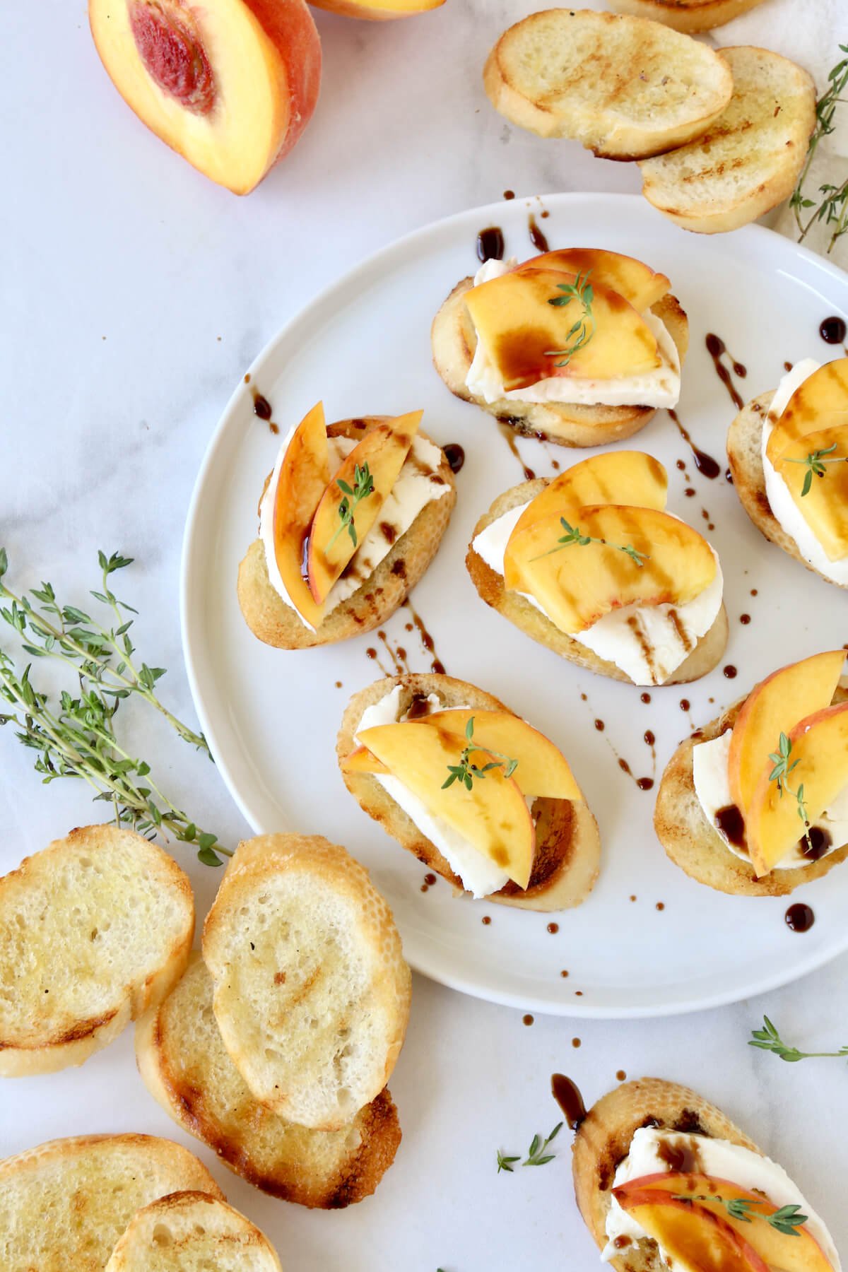 A round white place with toasted bread, mozzarella slices and sliced peaches.  