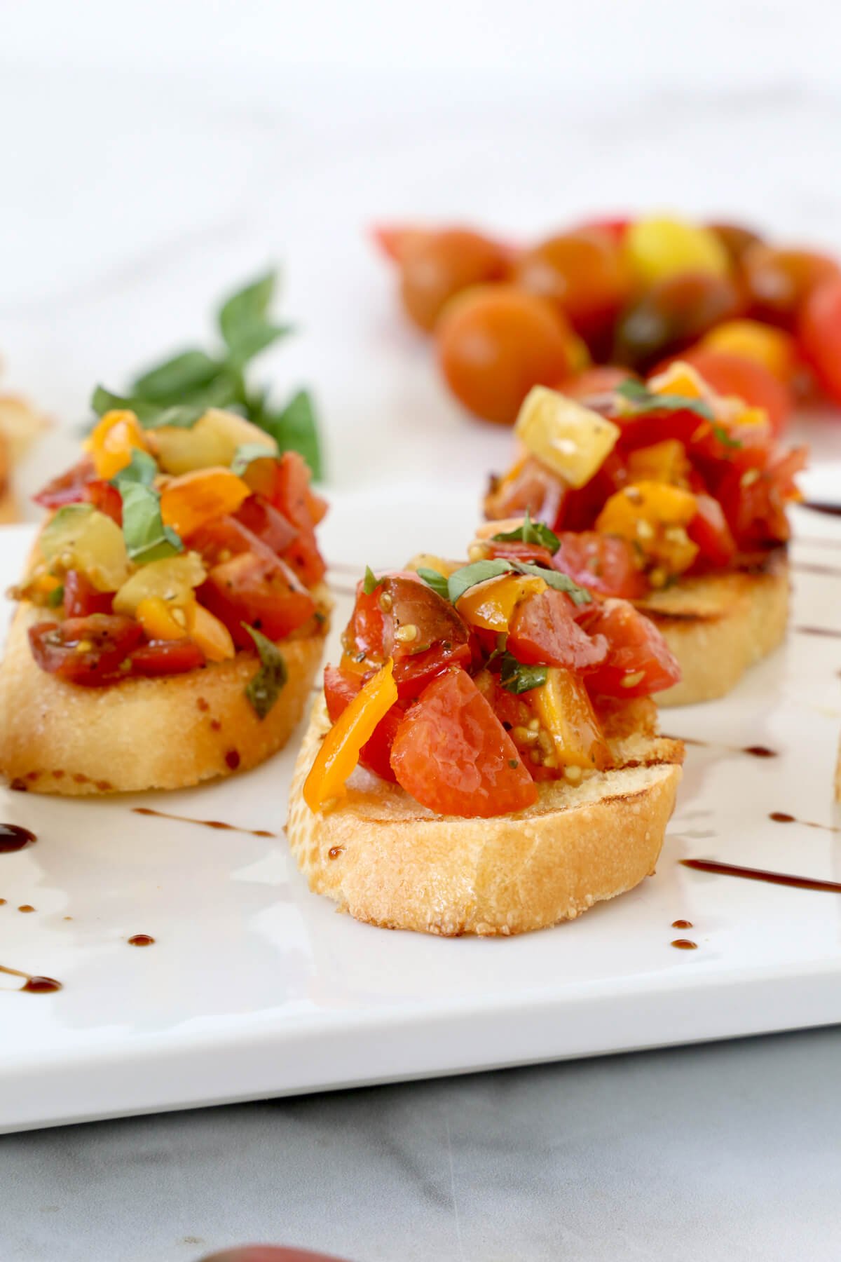 A white platter with toasted bread topped with chopped tomatoes 